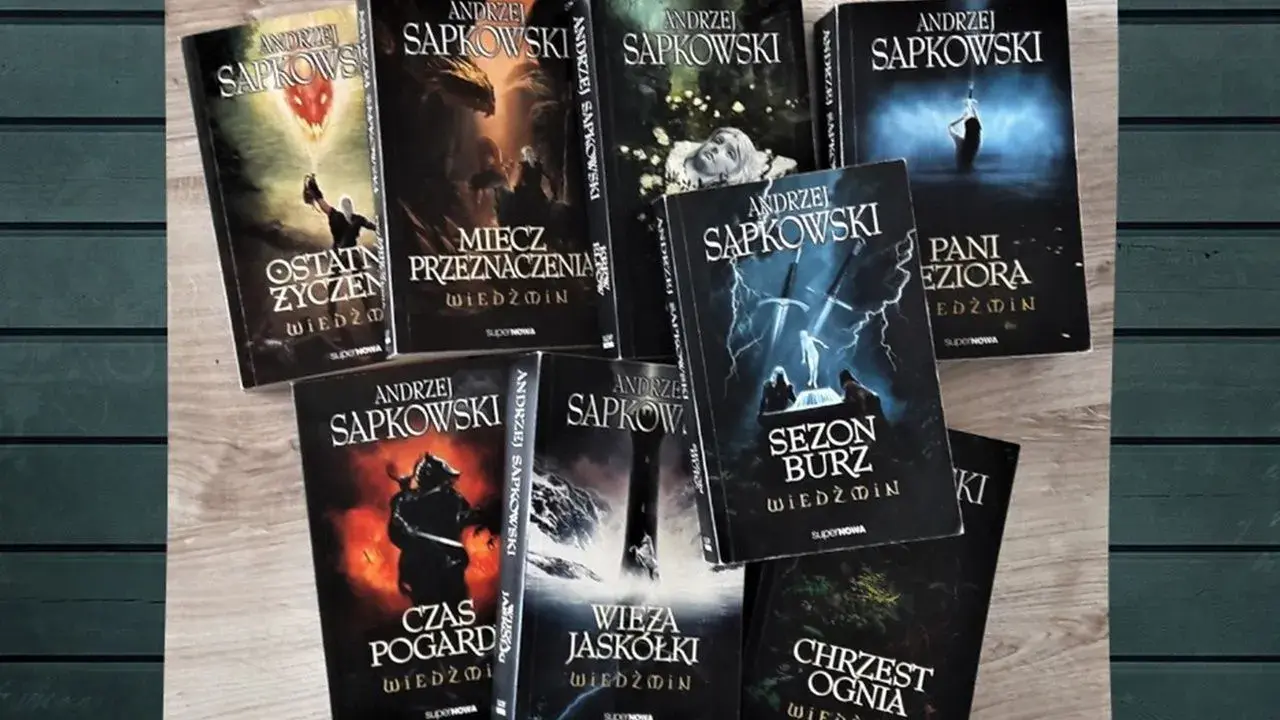 Książki Andrzeja Sapkowskiego z serii Wiedźmin ułożone na drewnianym tle.