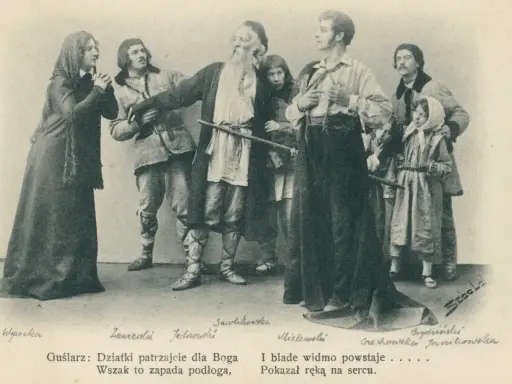 Grupa postaci w strojach ludowych, w tym starszy mężczyzna z brodą, młodzi ludzie i dzieci.