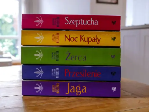 Pięć kolorowych książek Katarzyny Bereniki Miszczuk ułożonych jedna na drugiej. Na okładkach widnieje symbol kwiatu paproci.