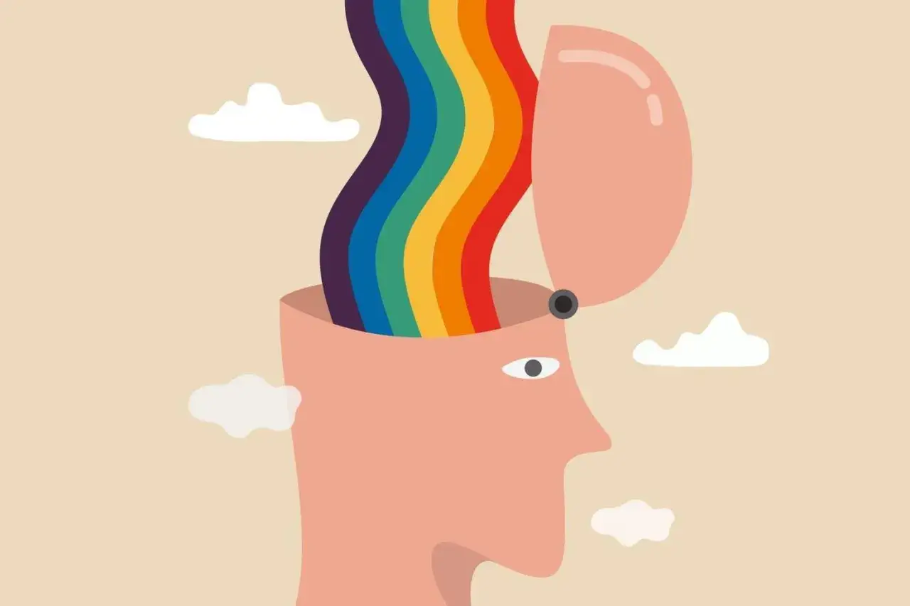 Otwarta głowa, z której wypływa tęcza emocji. Chmury unoszą się na beżowym tle.