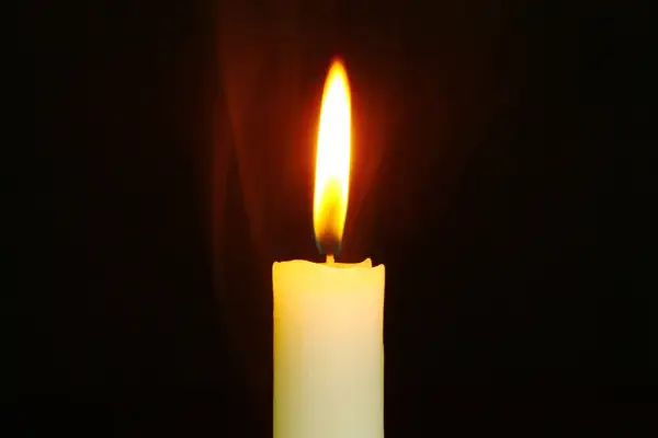 Jasny płomień świecy, niczym ulotna dusza, tańczy na tle ciemności, ogrzewając przestrzeń.