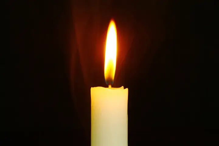 Jasny płomień świecy, niczym ulotna dusza, tańczy na tle ciemności, ogrzewając przestrzeń.